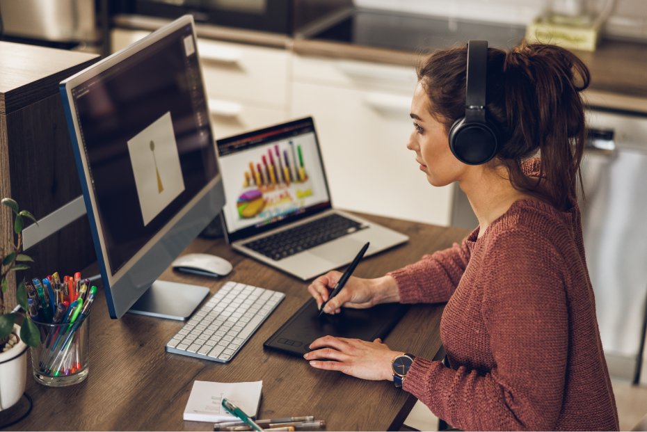 Mulher estudando marketing odontológico e tomando notas em frente a um computador desktop e um laptop